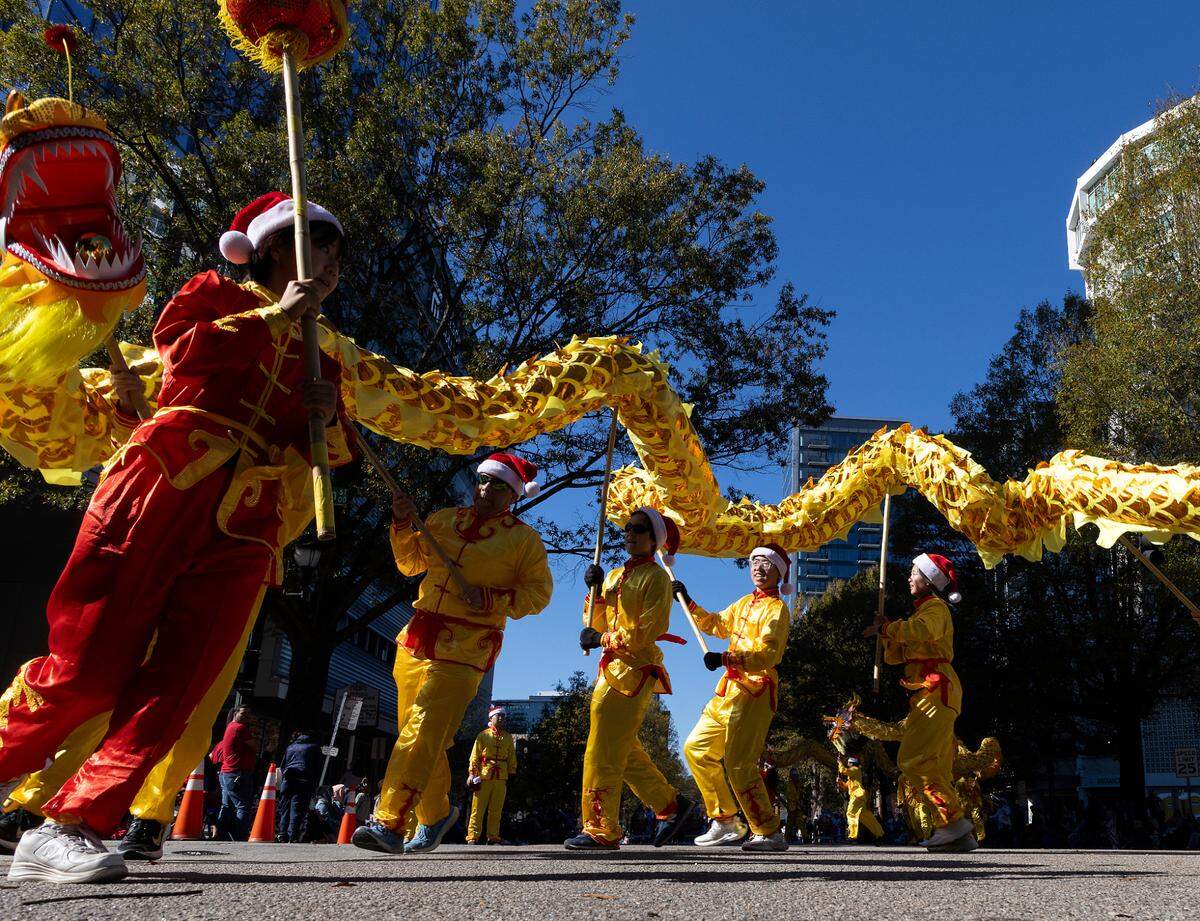 People hold a Chinese dragon aloft as they march down Hillsborough Street during the Raleigh Christmas Parade on Saturday, Nov. 18, 2023.
