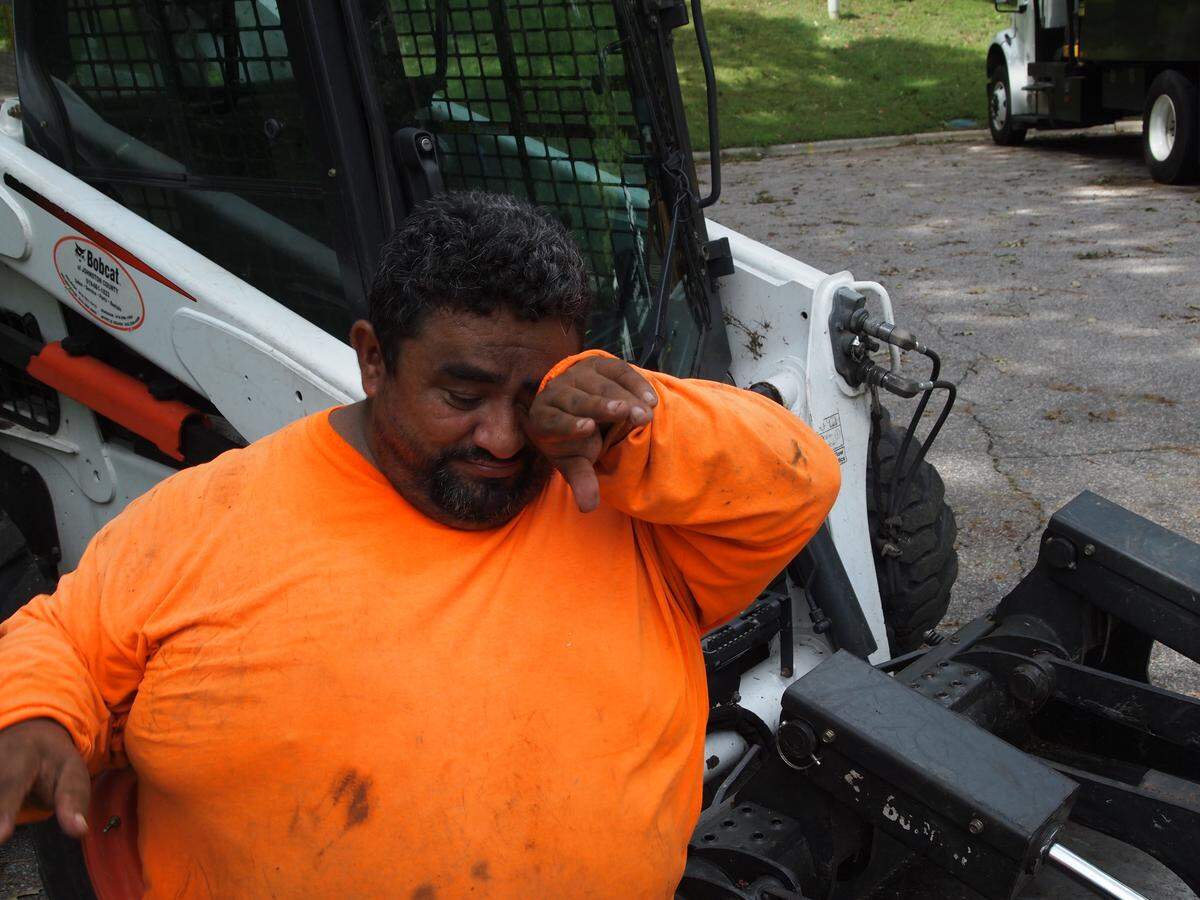 Bobcat operator Juan Santos wipes away sweat after clearing away tree debris in Raleigh in the wake of Hurricane Florence on Monday, Sept. 17, 2018.