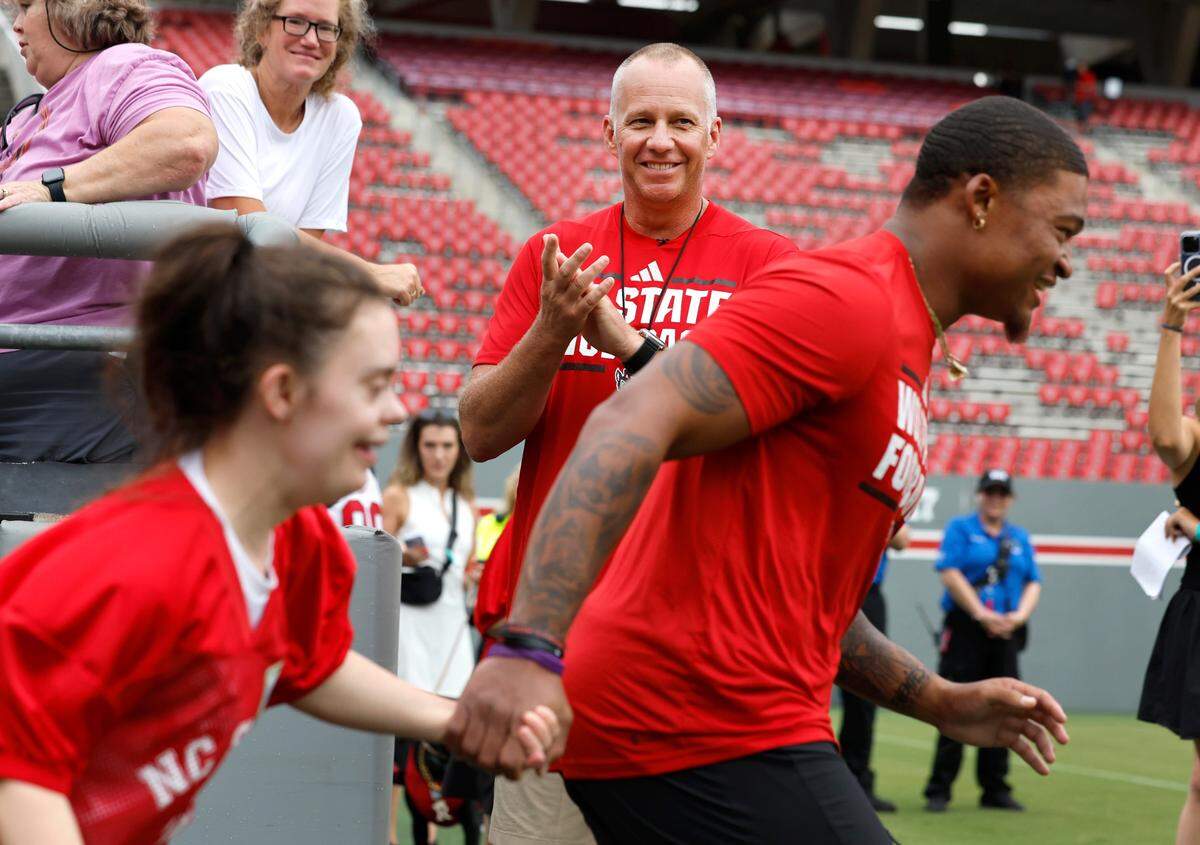 N.C. State head coach Dave Doeren applauds as players and attendees take the field during Victory Day at Carter-Finley Stadium in Raleigh, N.C., Friday, August 2, 2024. Victory Day is a partnership between the Wolfpack and GiGi’s Playhouse, a Down Syndrome achievement center in Raleigh. The event provided 52 cognitively and physically impaired people the chance to be football stars for the night. They tried on uniforms, met the players and coaches, ran through the tunnel and competed in drills with the players.