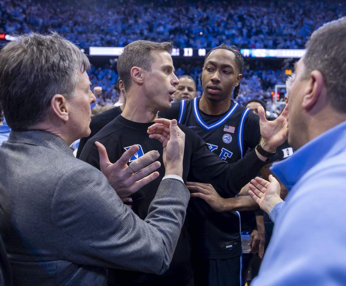 Duke coach Jon Scheyer and his players try to get off the Smith Center Court following a three-point shot by North Carolina guard Seth Trimble on Saturday, February 7, 2026 at the Smith Center in Chapel Hill, N.C.  Scheyer voiced his disappointment at not being able to get off the court safely at the end of the game once fans stormed the court. 