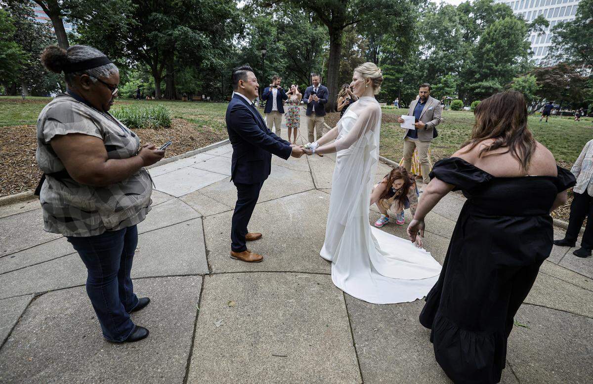 Rebecca Stewart and Billy Khantawong prepare to get married by Angela Davis, left, in Nash Square Park in Raleigh, N.C., Friday, May 22, 2026. The two had to move their wedding after the Wake County Justice Center closed early because of a shooting.