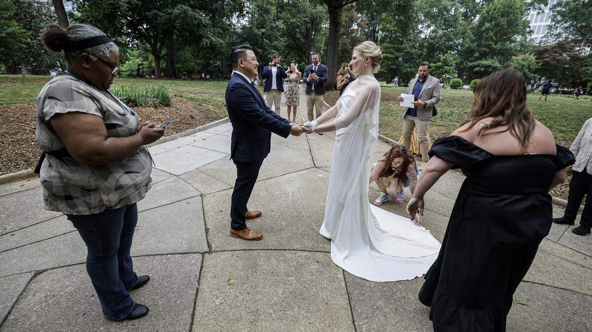 Rebecca Stewart and Billy Khantawong prepare to get married by Angela Davis, left, in Nash Square Park in Raleigh, N.C., Friday, May 22, 2026. The two had to move their wedding after the Wake County Justice Center closed early because of a shooting.