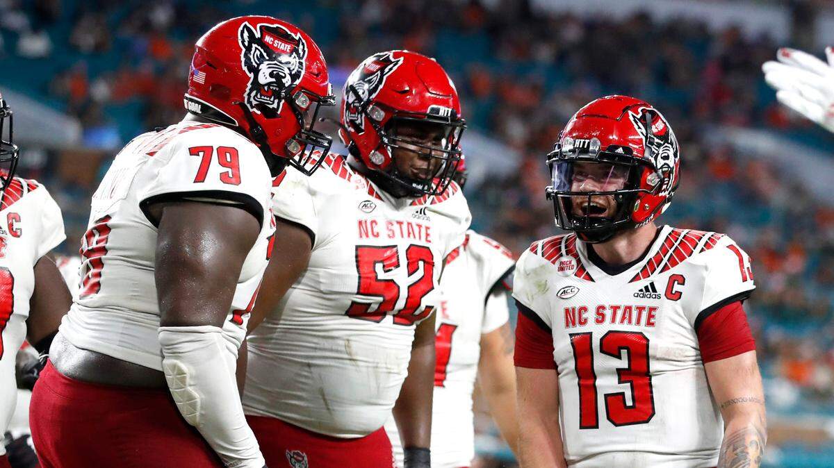 N.C. State quarterback Devin Leary (13) celebrates with Ikem Ekwonu (79) and Timothy McKay (52) after scoring on a 17-yard touchdown run during the second half of Miami’s 31-30 victory over N.C. State at Hard Rock Stadium in Miami Gardens, Fla. Saturday, Oct. 23, 2021.