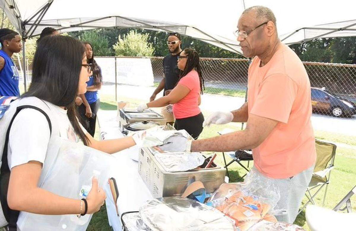 The pandemic-born pop-up hot dog stand QueDogs will open a brick and mortar location in Durham’s Lakewood neighborhod. The brand is owned by brother and sister Patrick Johnson and Kathryn Johnson Thompson, center, and their father Harold Johnson, right.
