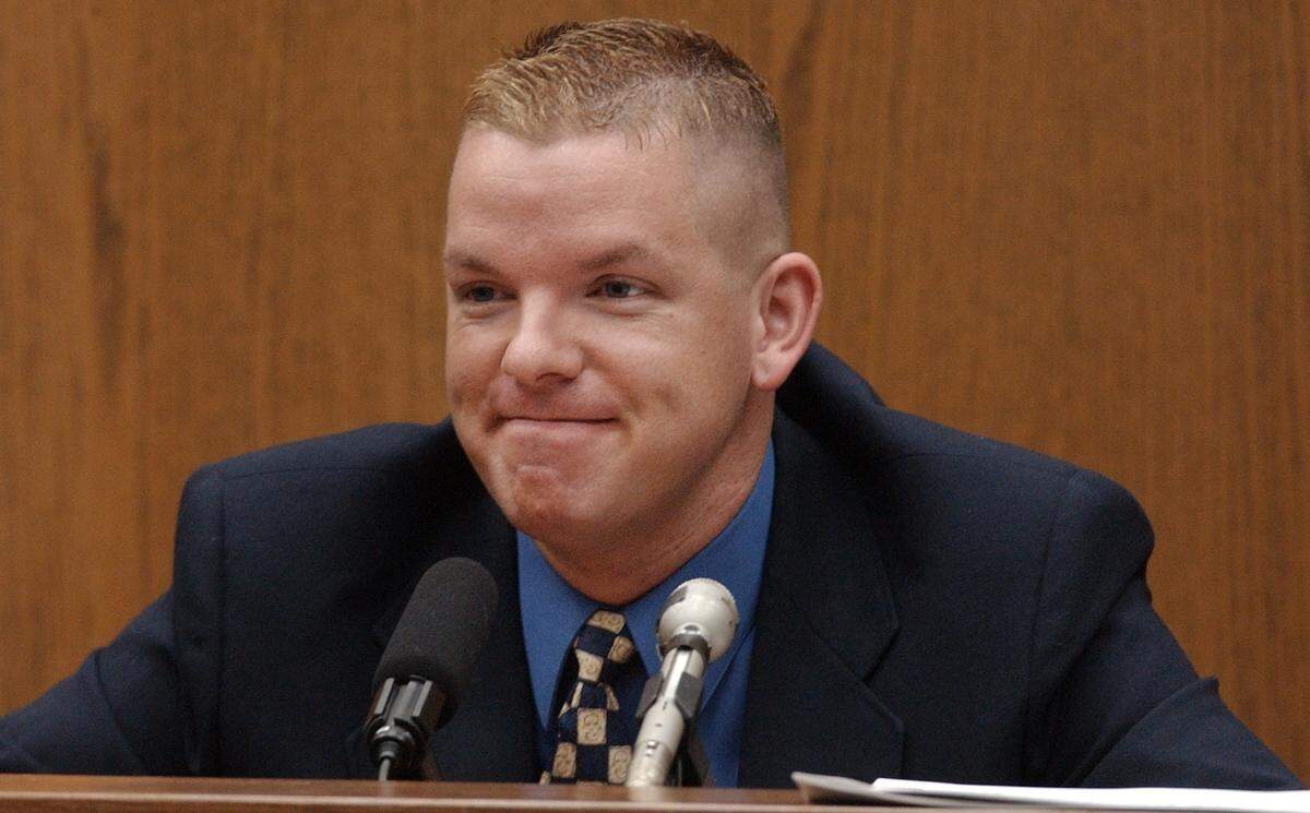 Self-described male escort Brent Wolgamott,28, of Raleigh, N.C. grins at defense attorney David Rudolf after saying some of his “clients” were doctors and lawyers and even one judge during his testimony Monday in the Michael Peterson murder trial.