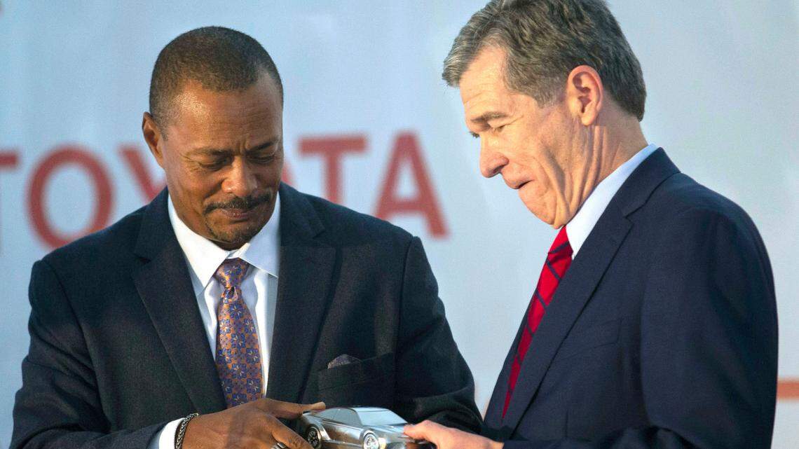 Toyota Motor Administrative Officer Chris Reynolds, left, presents North Carolina Gov. Roy Cooper with a model race car as a gift celebrating their new partnership during the announcement of a new Toyota battery manufacturing plant in Liberty, N.C., Monday, Dec. 6, 2021. 