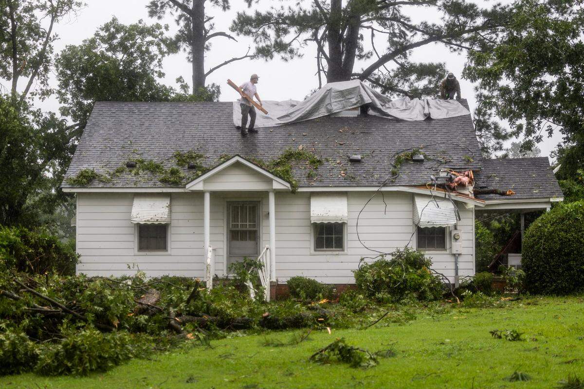 Workers place tarps over the damaged roof of former Gov. Jim Hunt’s childhood home in Rock Ridge on Thursday, Aug. 8, 2024 after a tornado damaged a school and at least ten homes in Wilson County. At least one person was killed as a result of the tornado.