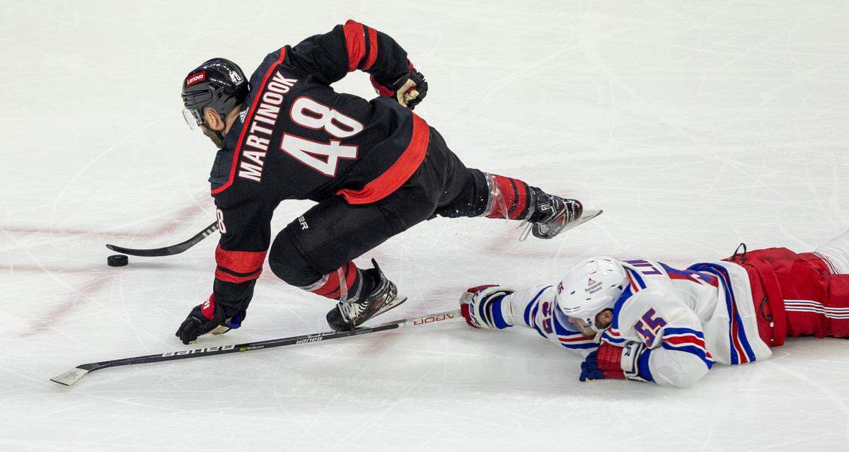 New York Rangers defenseman Ryan Lindgren (55) trips Carolina Hurricanes left wing Jordan Martinook (48), setting up a power play at 16:17 in the third period during Game 4 in the second round of the 2024 Stanley Cup playoffs on Saturday, May 11, 2024 at PNC Arena, in Raleigh N.C.
