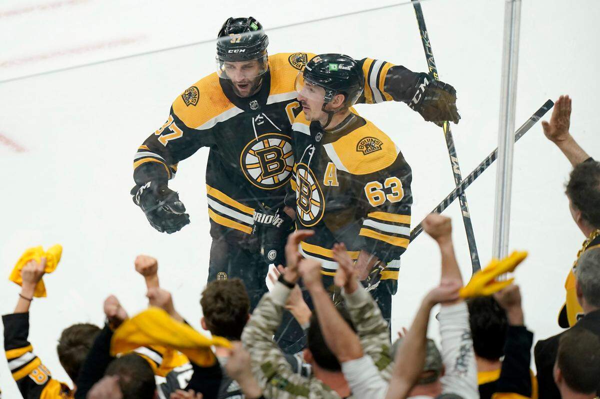 Boston Bruins’ Patrice Bergeron, top left, celebrates with Brad Marchand, right, after Marchand scored in the third period of Game 4 of an NHL hockey Stanley Cup first-round playoff series against the Carolina Hurricanes, Sunday, May 8, 2022, in Boston. (AP Photo/Steven Senne)