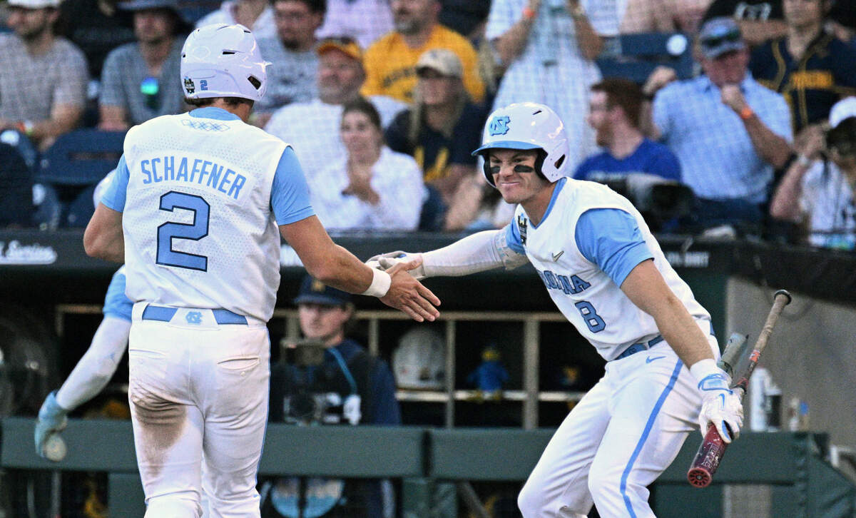 North Carolina Tar Heels shortstop Jake Schaffner (2) and center fielder Owen Hull (8) celebrate scoring against the West Virginia Mountaineers during the seventh inning at Charles Schwab Field.