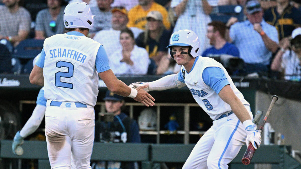 North Carolina Tar Heels shortstop Jake Schaffner (2) and center fielder Owen Hull (8) celebrate scoring against the West Virginia Mountaineers during the seventh inning at Charles Schwab Field.