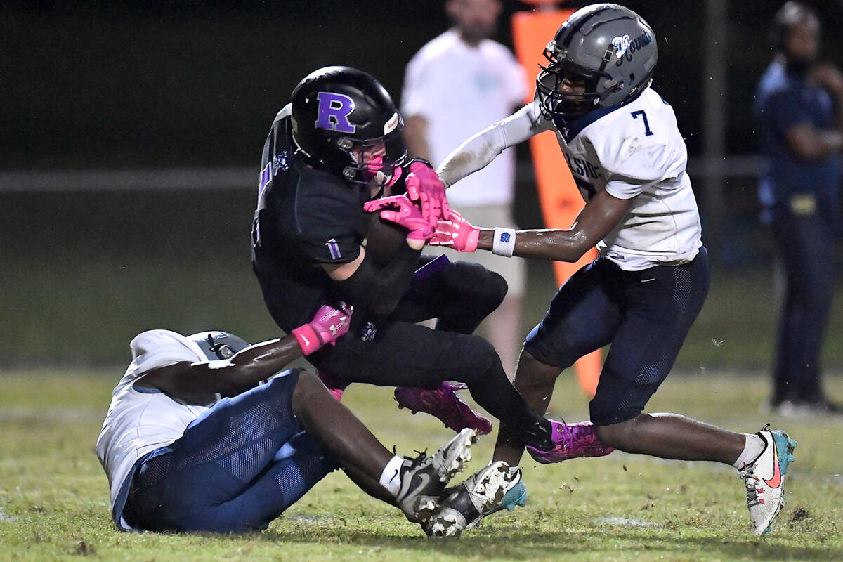 Riverside wide receiver Cole Schweitz (1) gets the first down off a pass reception against Hillside’s Kaleb Lott (7) and Kaleb Lott (8) during the second half. The Durham Hillside Hornets and the Durham-Riverside Pirates met in a football game in Durham. N.C. on October 4, 2024.