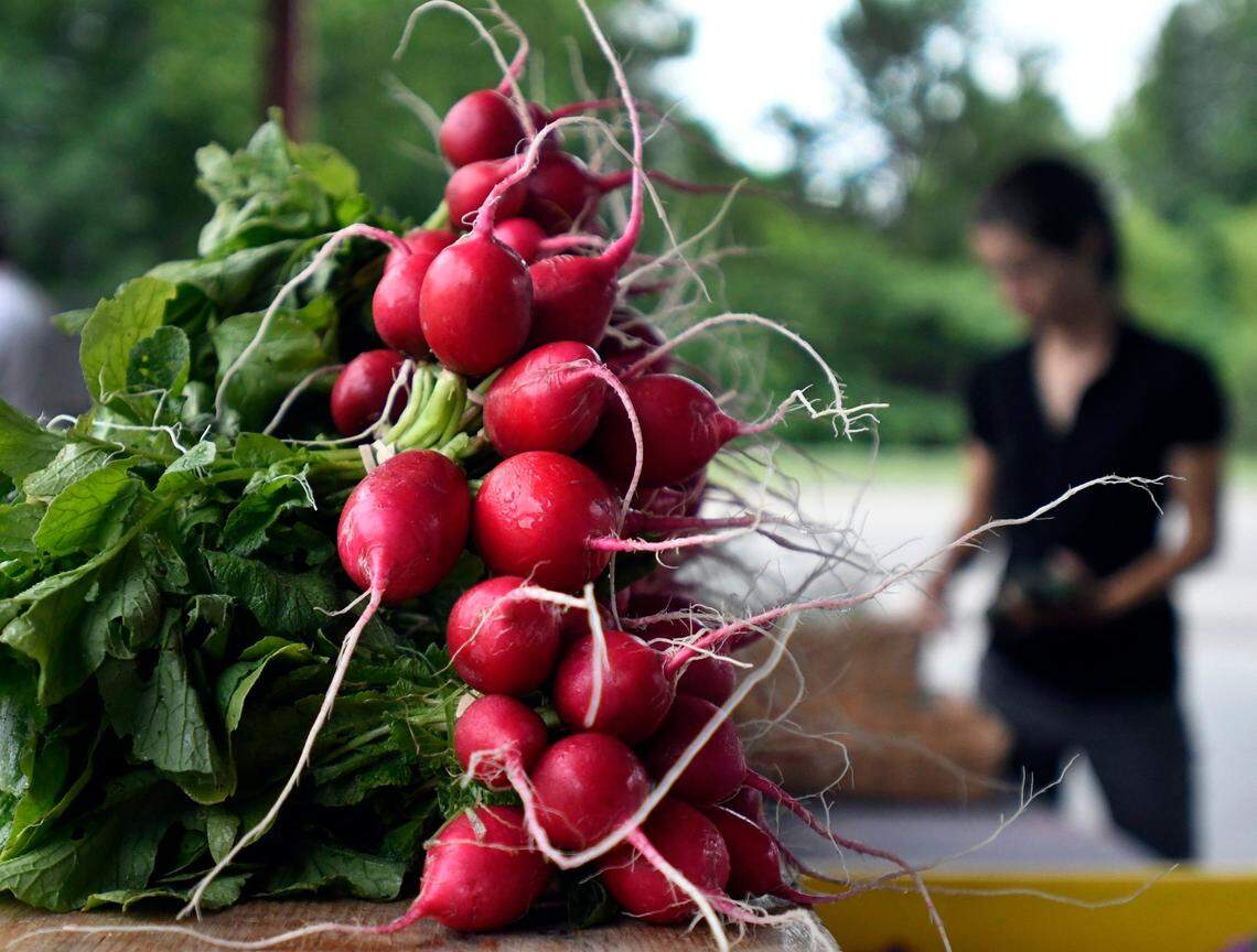 Lydie Costes from Maple Springs Gardens sets up her produce, including bunches of radishes, at the Durham Farmer’s Market in Durham in 2017.
