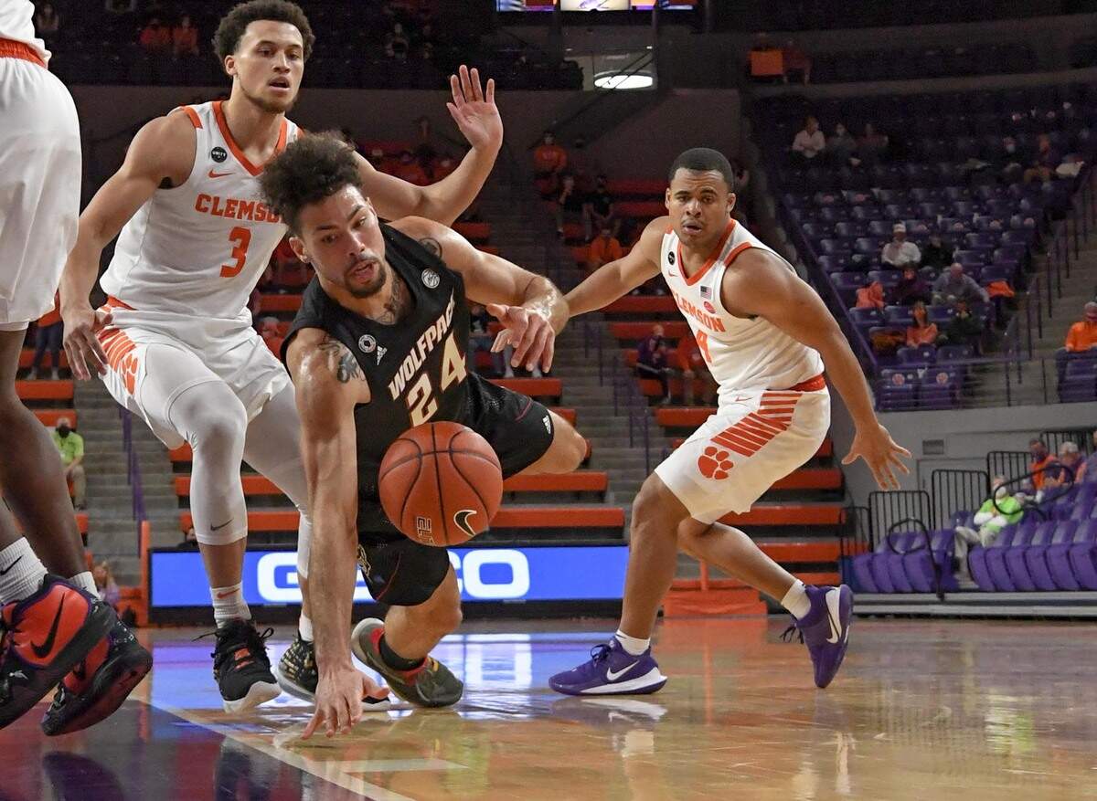 NC State guard Devon Daniels(24) loses control of the ball near Clemson sophomore guard Chase Hunter(3) and Clemson sophomore guard Nick Honor(4) during the first half of their game Jan. 5, 2021.