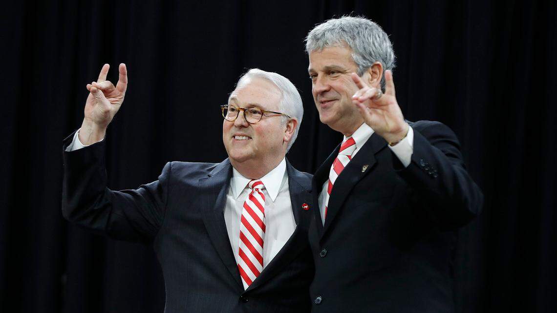 N.C State chancellor Randy Woodson, left, and Athletic Director Boo Corrigan give the Wolfpack sign.