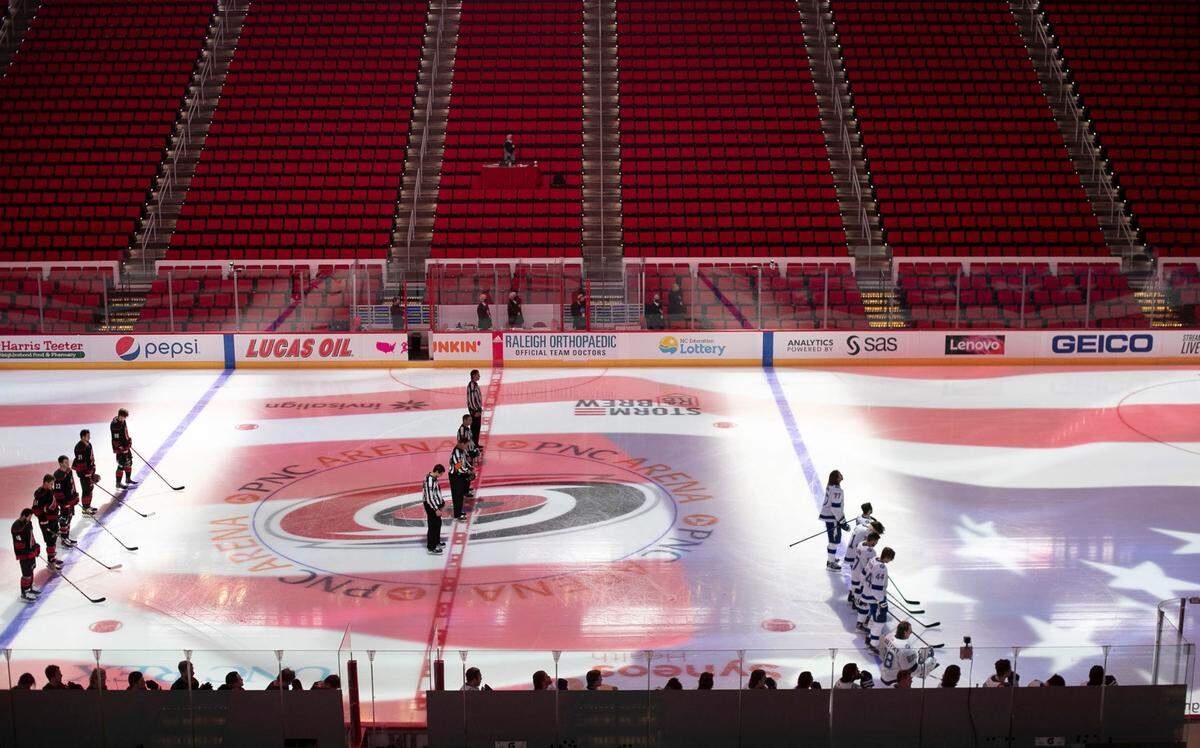The Carolina Hurricanes and the Tampa Bay Lightning stand for the National Anthem prior to the Hurricanes’ season home opener without fans on Thursday, January 28, 2021 at PNC Arena in Raleigh, N.C.