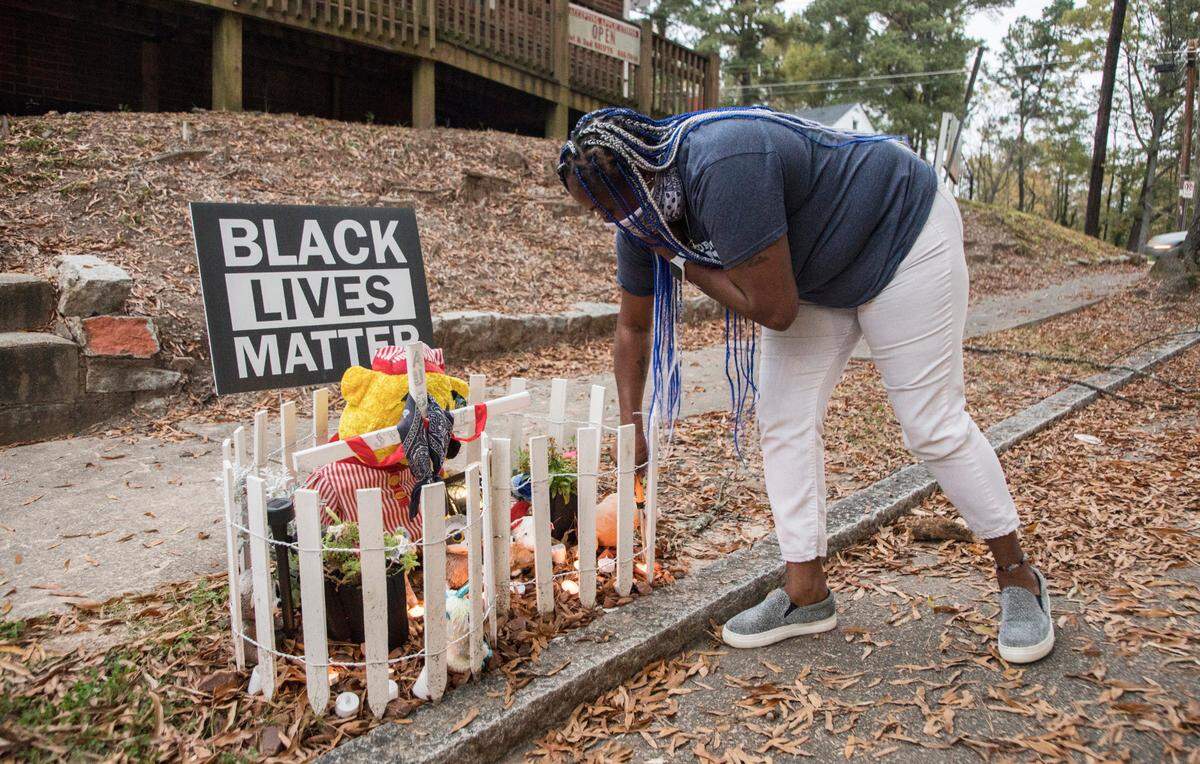 Lavern Lucier lights candles on November 9, 2020 at a memorial she created for her son, Syncere Burrell. Burrell was shot and killed where the memorial sits, near the corner of Lincoln St. and Linwood Ave. in Durham, N.C. on August 10, 2020.