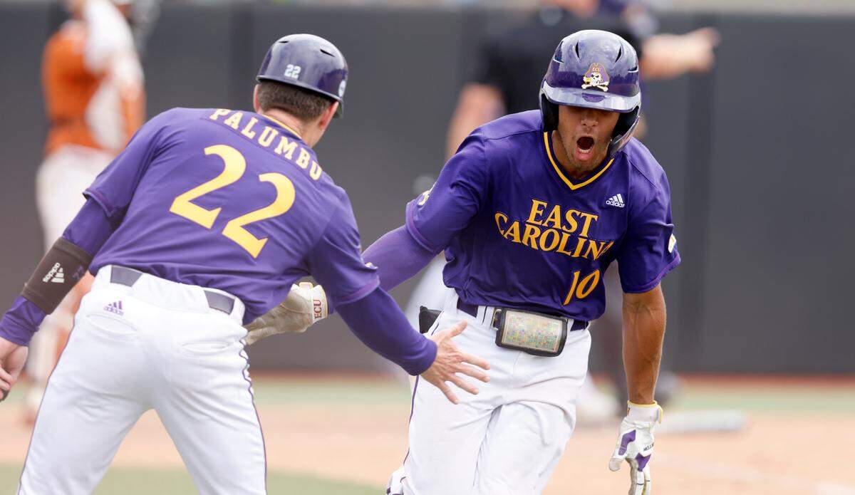 East Carolina’s Jacob Starling (10) celebrates with assistant head coach Jeff Palumbo as he rounds first base after hitting a solo homerun in the ninth inning during Texas’ 9-8 victory over ECU in the Greenville Super Regional at Clark-LeClair Stadium Saturday, June 11, 2022.