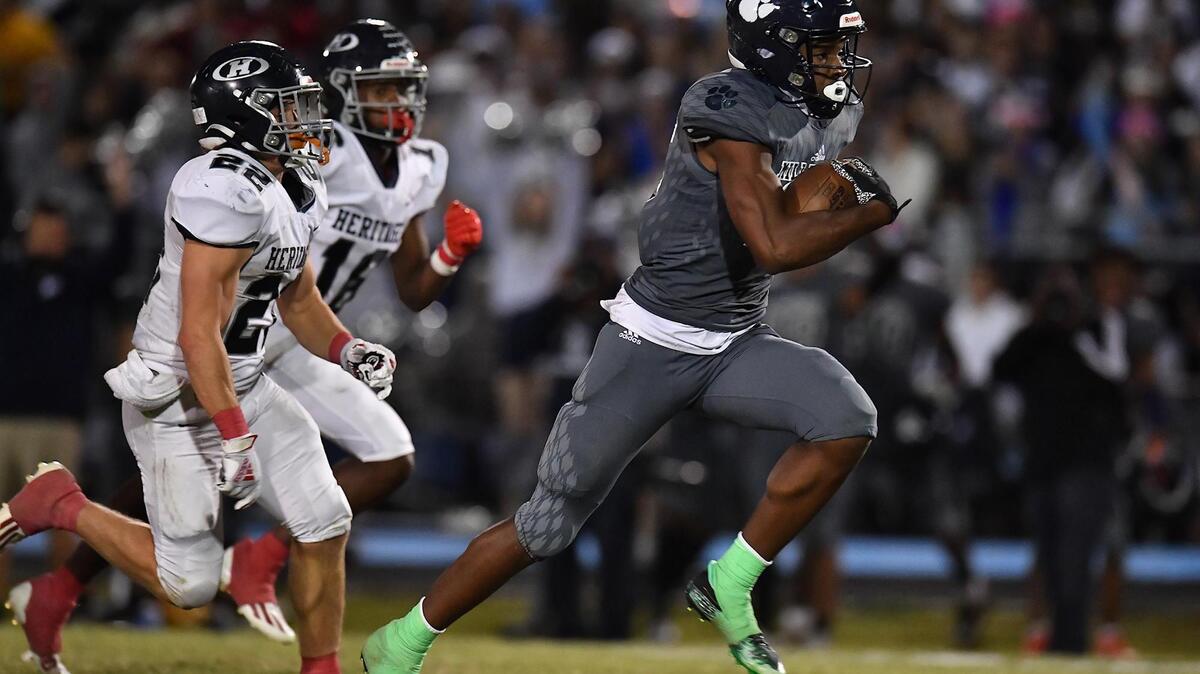 Millbrook’s Nathan Leacock (15) sprints for the touchdown ahead of Heritage’s Coleson Fields (22) in the second half. The Millbrook Wildcats and the Heritage Huskies met in a football game in Raleigh, N.C. on September 29, 2022.