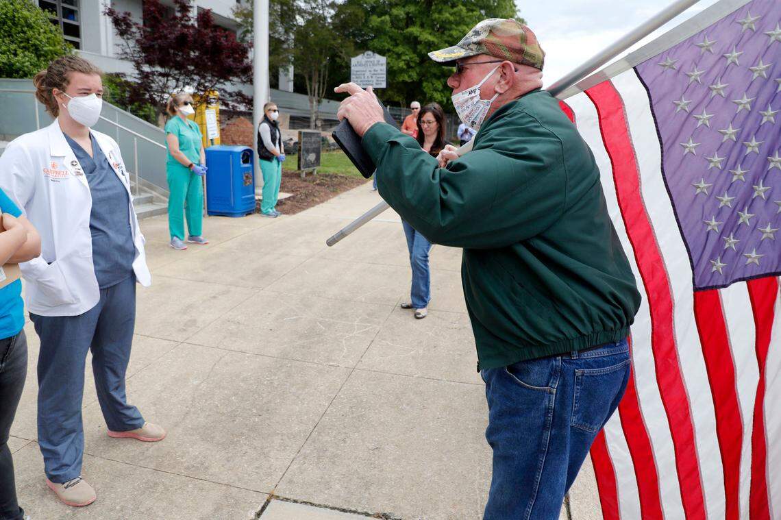 A protester, who did not want to give his name, yells at medical student Carrie Shropshire and others during the ReOpenNC protest in downtown Raleigh, N.C., Tuesday, April 21, 2020.