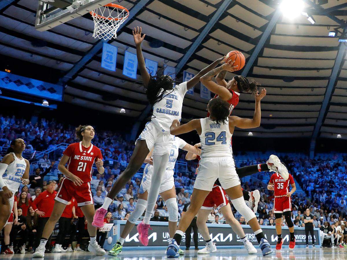 N.C. State’s Aziaha James drives to the basket against North Carolina’s Maria Gakdeng and Indya Nivar during the second half of the Wolfpack’s 80-70 loss on Thursday, Feb. 22, 2024, at Carmichael Arena in Chapel Hill, N.C.