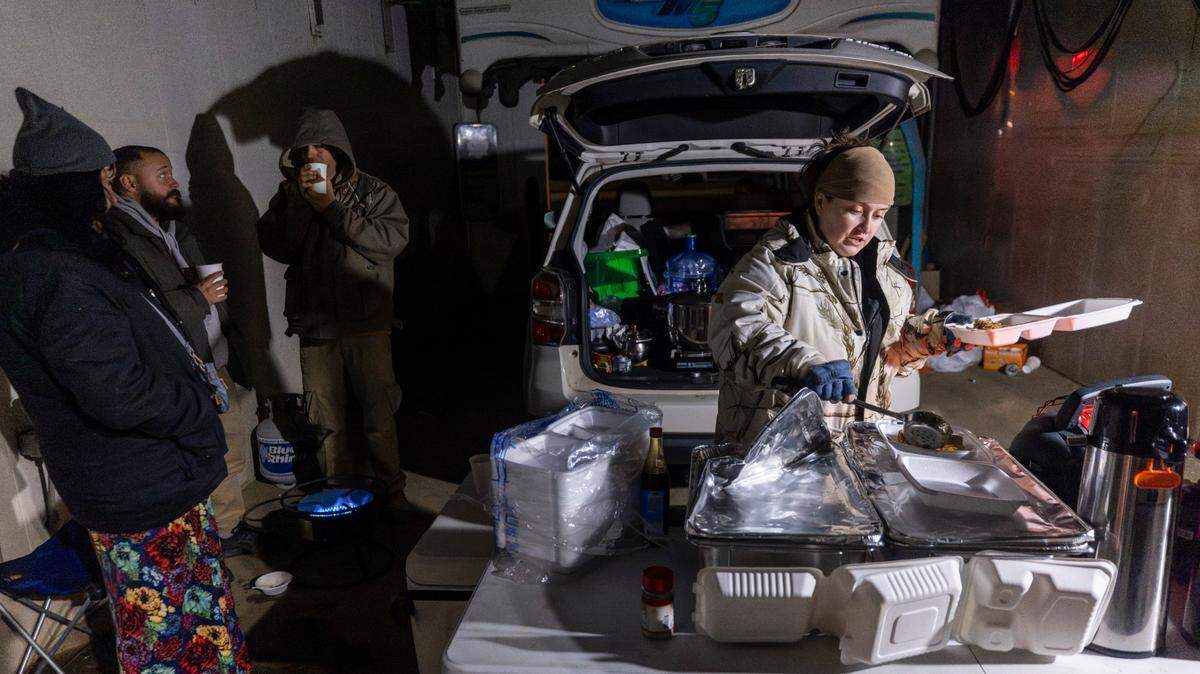 Cayte Gowan, right, serves free hot meals from the back of her car at an Ingles car wash in Swannanoa on Friday evening, Dec. 6, 2024. Gowan has been providing free meals in the community since the days immediately following the devastation caused by Hurricane Helene.
