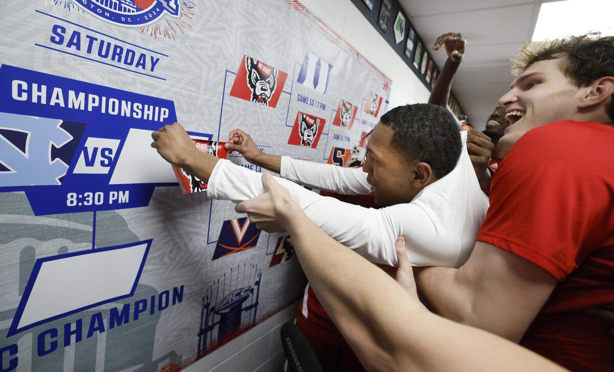 N.C. State's KJ Keatts is lifted to put the Wolfpack sticker on the wall after N.C. State’s 72-65 overtime victory over Virginia in the semifinals of the 2024 ACC Men’s Basketball Tournament at Capital One Arena in Washington, D.C., Friday, March 15, 2024.