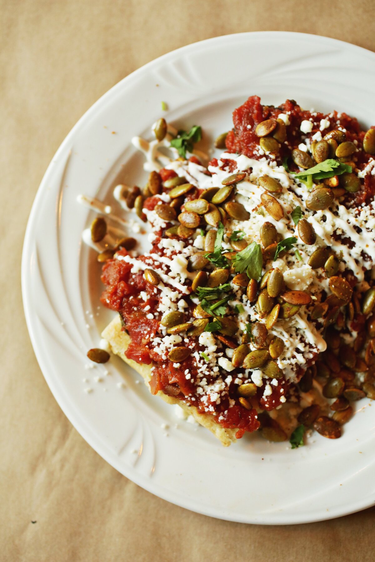 The Braza la Reina is cooked sans corn husk, and topped with a patchwork of house-made salsa roja, cilantro, crema, queso and pepitas at Tamale Factory and Tequila Bar in Durham.