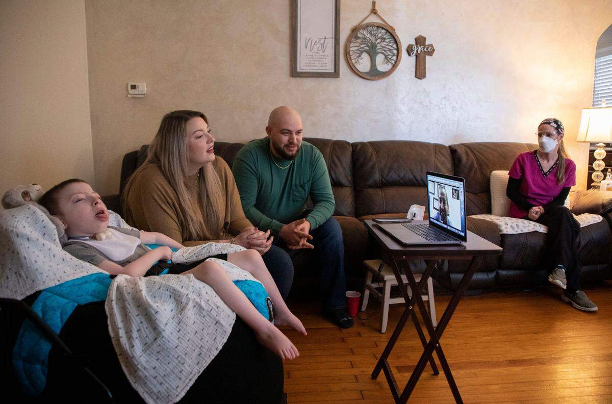 Duke Health’s Dr. Sujay Kansagra conducts a telehealth visit with Claudia Moore and Michael Yannotti, middle left, for their son Boston Yannotti, 5, who has AADC deficiency and requires home health care from his nurse, Missy Bailey, right, in their home in Eden, N.C. on March 9, 2022.