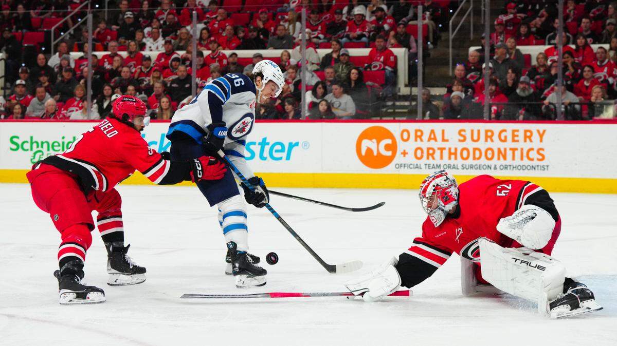Mar 2, 2024; Raleigh, North Carolina, USA; Carolina Hurricanes goaltender Pyotr Kochetkov (52) and defenseman Jalen Chatfield (5) stop the scoring attempt by Winnipeg Jets center Morgan Barron (36) during the second period at PNC Arena. Mandatory Credit: James Guillory-USA TODAY Sports