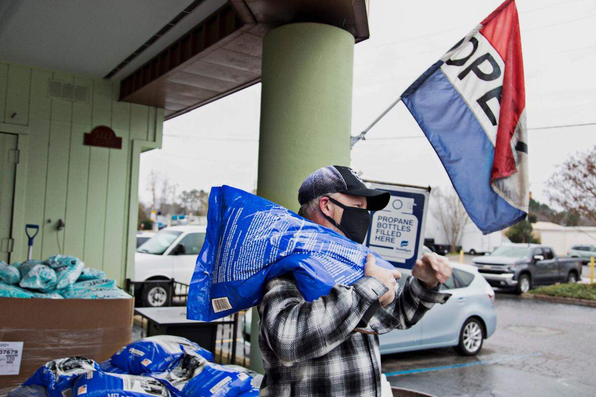 Burke Brothers Hardware employee Steve Lee, throws salt over a shoulder to load into a car for a customer on Thursday morning, Jan. 20, 2022, in advance of anticipated snow.