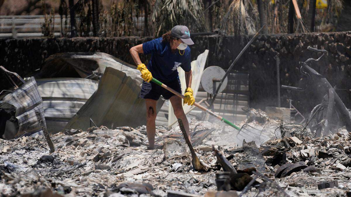A woman digs through rubble of a home destroyed by a wildfire, Friday, Aug. 11, 2023, in Lahaina, Hawaii. Hawaii increasingly seems under siege from disasters, and what is increasing most is wildfire, according to an analysis of Federal Emergency Management Agency records by The Associated Press. There were as many federally-declared disaster wildfires this month in Hawaii, as in the 50 years between 1953 and 2003.