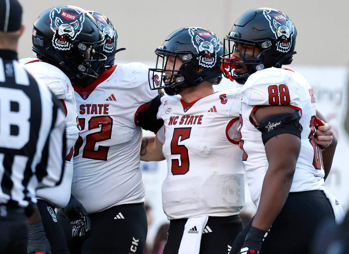 N.C. State quarterback Brennan Armstrong (5) celebrates with Anthony Carter Jr. (75), Timothy McKay (52) and Isaiah Shirley (88) after scoring on a one-yard touchdown run during the first half of N.C. State’s game against Virginia Tech at Lane Stadium in Blacksburg, VA, Saturday, Nov. 18, 2023.
