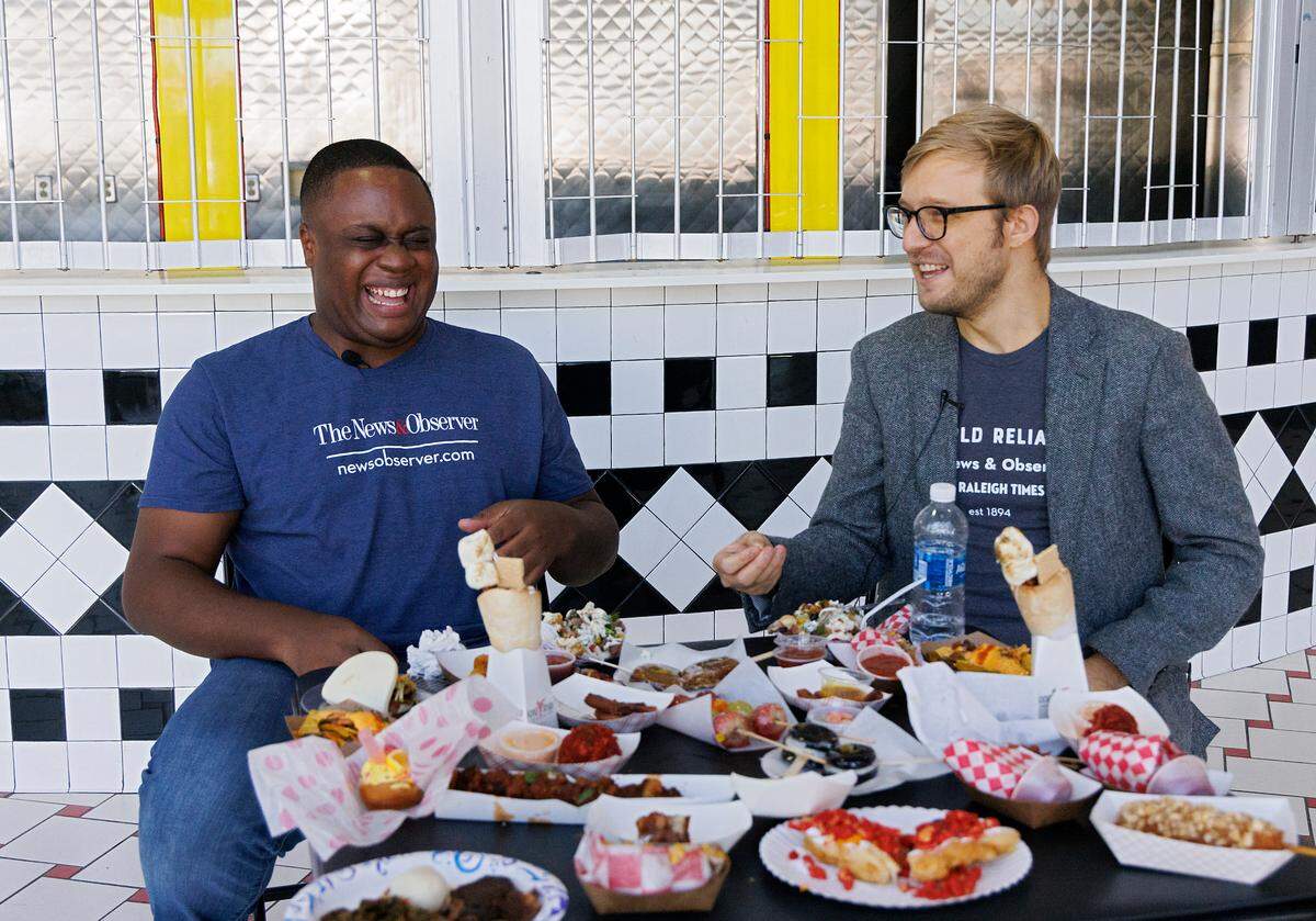 Evan Moore, service journalism reporter for The Charlotte Observer, and Drew Jackson, food reporter for The News & Observer, share a laugh while sampling new foods available at the 2024 North Carolina State Fair during media day on Monday, Oct. 14, 2024, in Raleigh, N.C.