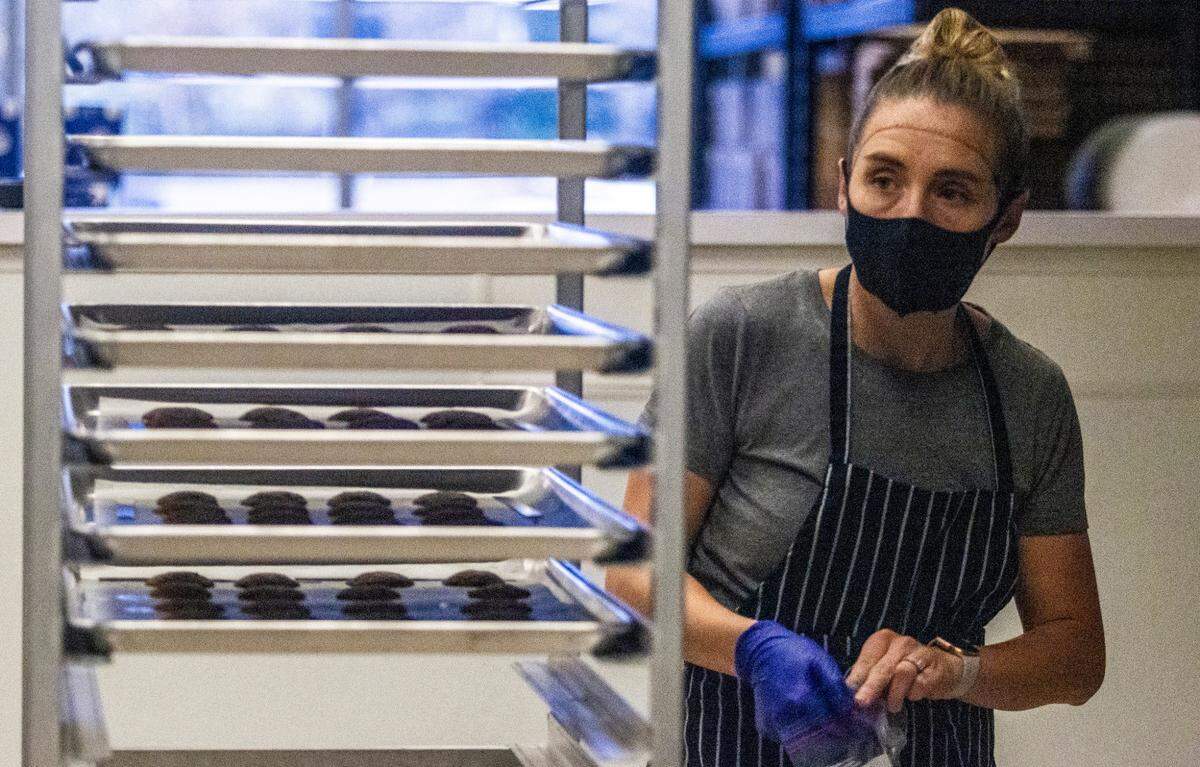 Brooke Navarro takes a sample cookie from a cooling rack at Without A Trace Foods in Raleigh Tuesday, Dec. 15, 2020. The startup makes allergy-free snacks.