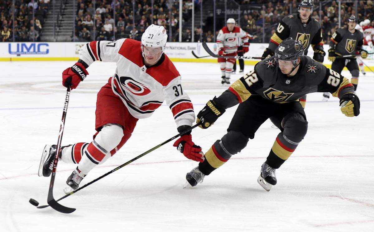 Vegas Golden Knights defenseman Nick Holden (22) and Carolina Hurricanes right wing Andrei Svechnikov (37) reach for the puck during the third period of an NHL hockey game Saturday, Nov. 3, 2018, in Las Vegas.