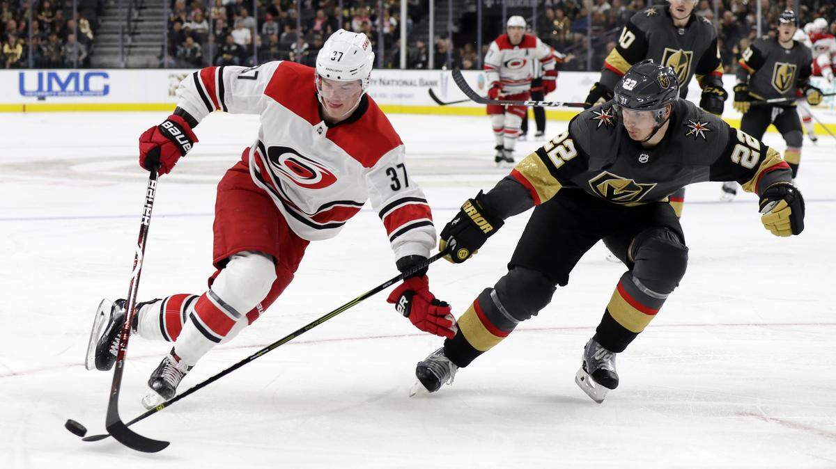 Vegas Golden Knights defenseman Nick Holden (22) and Carolina Hurricanes right wing Andrei Svechnikov (37) reach for the puck during the third period of an NHL hockey game Saturday, Nov. 3, 2018, in Las Vegas.