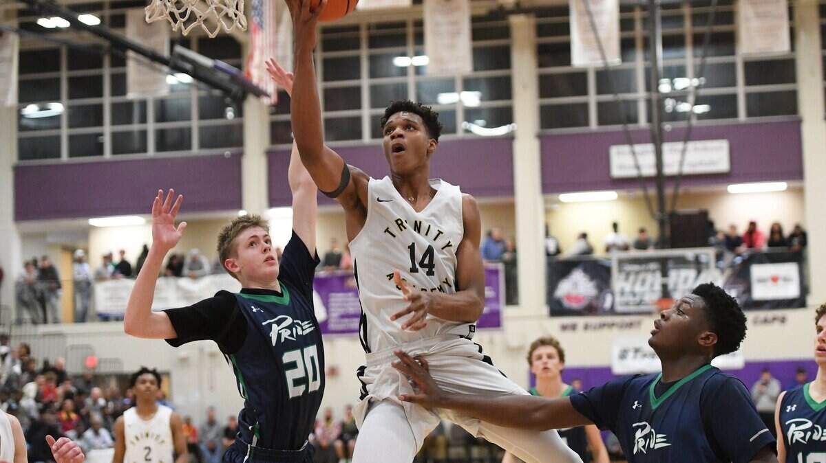 Isaiah Todd (14) of Trinity Academy scores with a layup against Alec Carawan (20) and RJ Wilson (24) of Leesville Road. The Trinity Academy Tigers played the Leesville Road Pride in a high school basketball game that was part of the John Wall Holiday Invitational Tournament in Raleigh, N.C. on December 26, 2018.