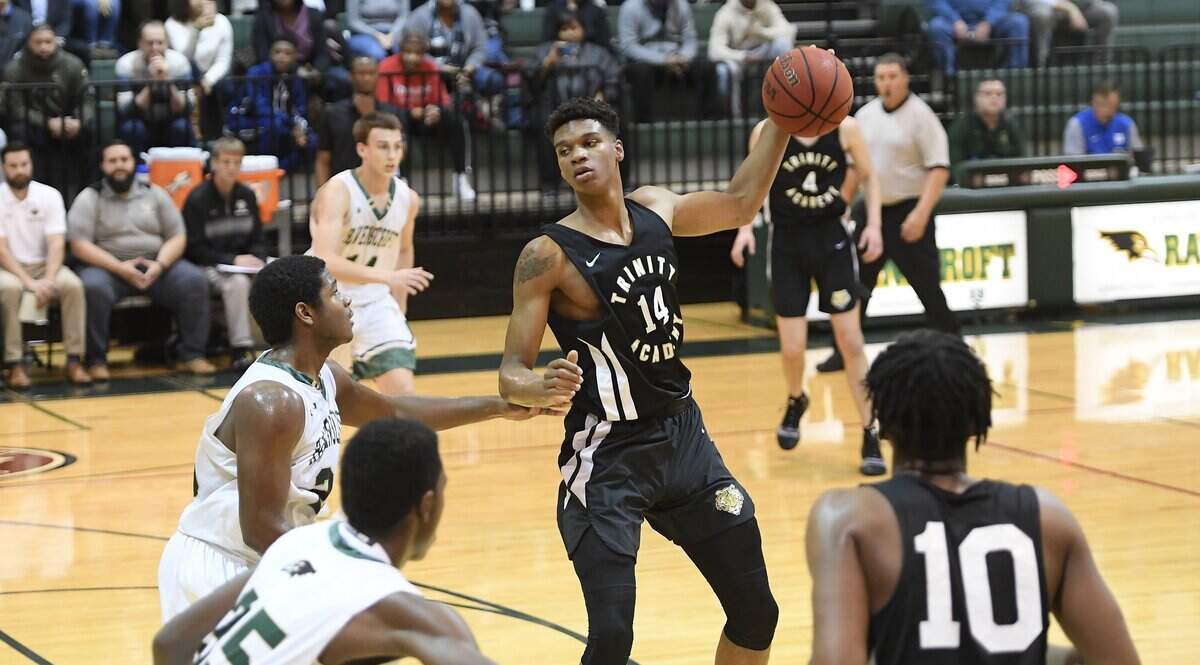 Isaiah Todd (14) of Trinity Academy looks for a pass against Jeremiah Williams, second from left, and Lucrichard Rameau, left, of Ravenscroft. The Trinity Academy Tigers visited the Ravenscroft Ravens in a high school boys basketball game on November 27, 2018. Trinity Academy won 65-64.