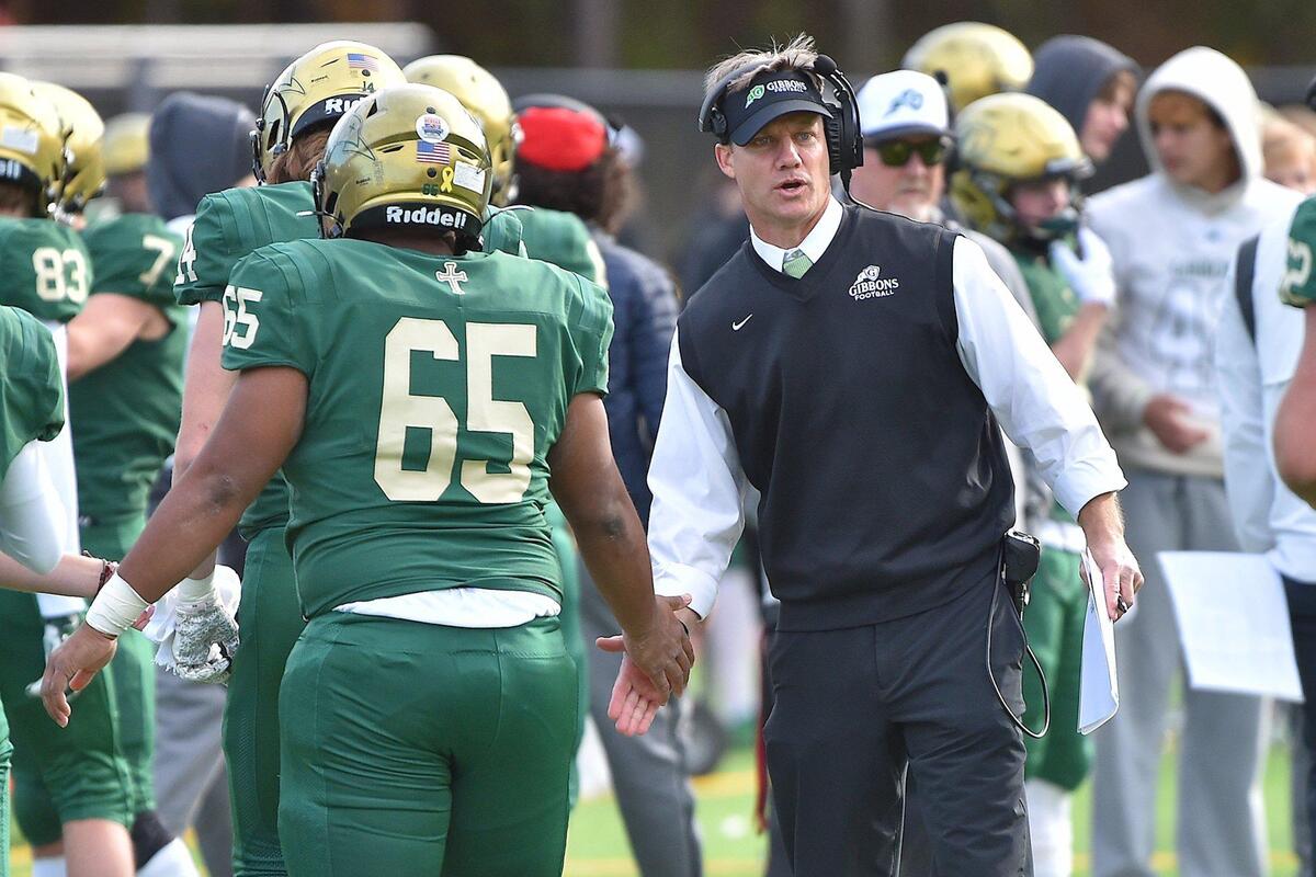 Cardinal Gibbons head football coach Steven Wright congratulates Jonathan Ward (65) during the second half. The Cardinal Gibbons Crusaders and the Panther Creek Catamounts met in the fourth round of the NCHSAA 4A playoffs in Raleigh, N.C. on November 26, 2021.