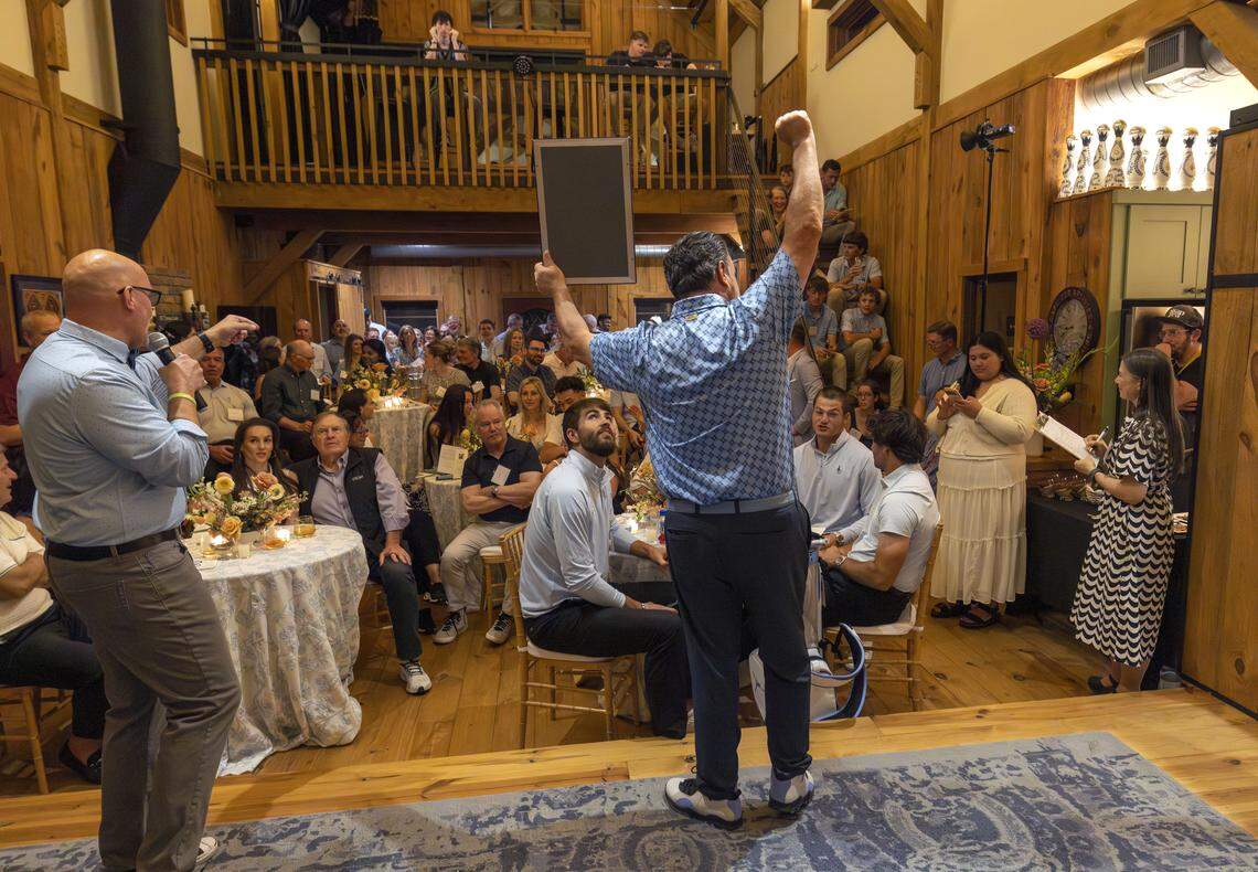 Scott Peterson, left, and Vaughn Moore auction off memorabilia during a fundraiser for TABLE, a non-profit that addresses food insecurities of children and families in Orange County, on Friday, April 17, 2026 in Carrboro, N.C.