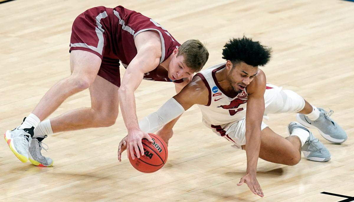 Colgate’s Tucker Richardson (15) and Arkansas’ Justin Smith (0) dive for a loose ball during the second half of a first round game at Bankers Life Fieldhouse in the NCAA men’s college basketball tournament, Friday, March 19, 2021, in Indianapolis. 