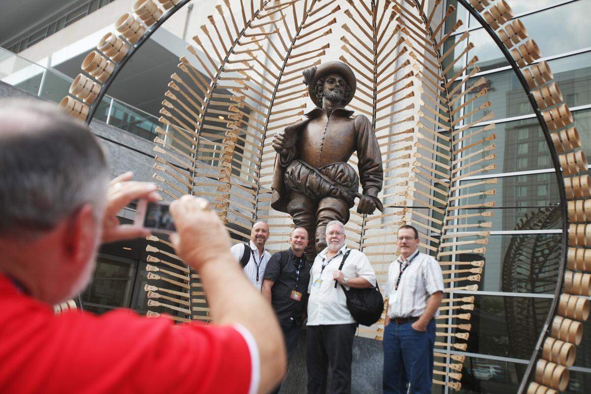 Willie T. Sorrell III, left, takes a photo of bluegrass band, None of the Above from Pinnacle, NC, in front of the Sir Raleigh Walter statue Thursday afternoon, October 2, 2014. Someone nabbed the festive cutout of a banjo from around the statue’s neck Wednesday evening.