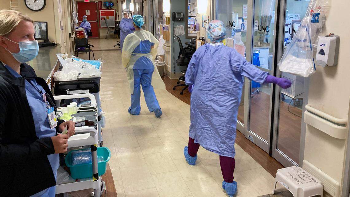 Staff in the COVID area of the Medical ICU unit at UNC Hospital move to work with a patient in the unit, Monday, July 13, 2020.