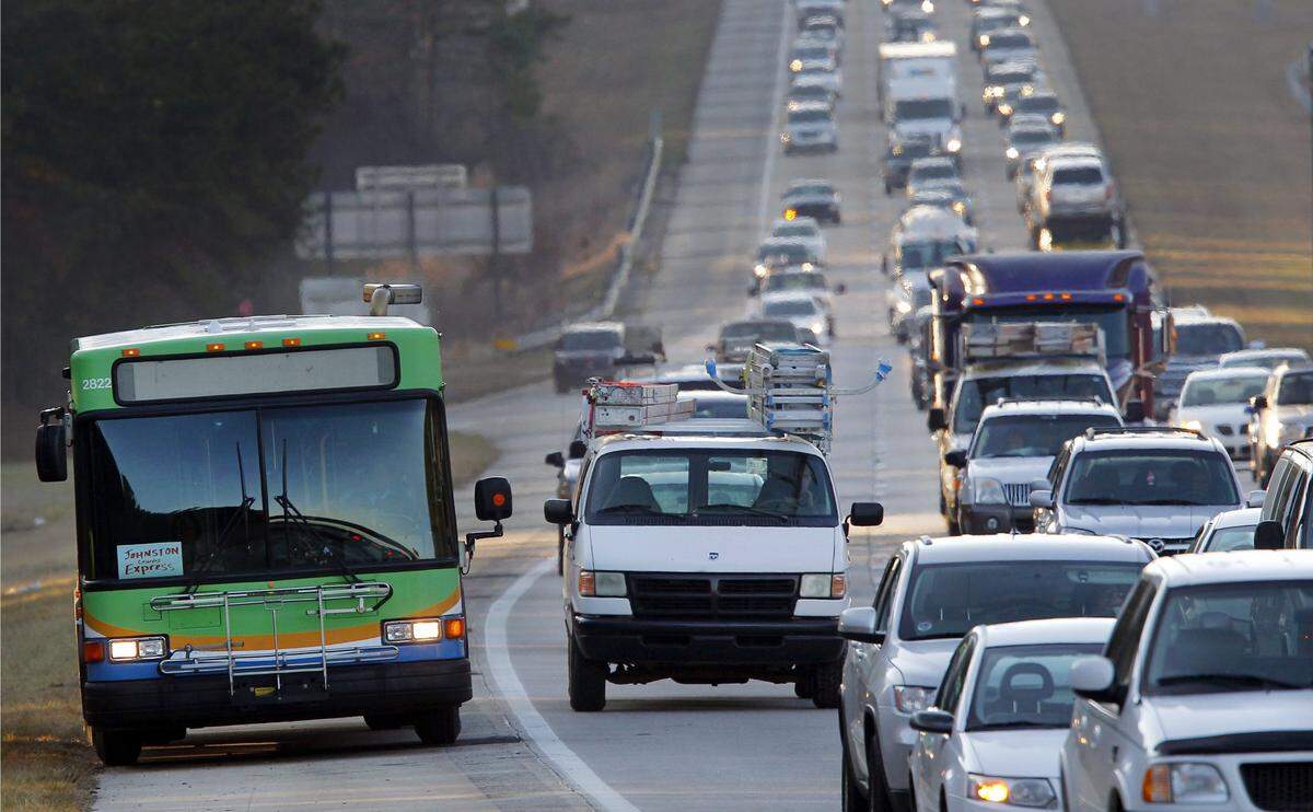 A TTA bus, with a “Johnston Express” sign in the front window, drives up the shoulder as traffic slows to a crawl on I-40 inbound from Johnston County and southern Wake County during morning rush-hour traffic.