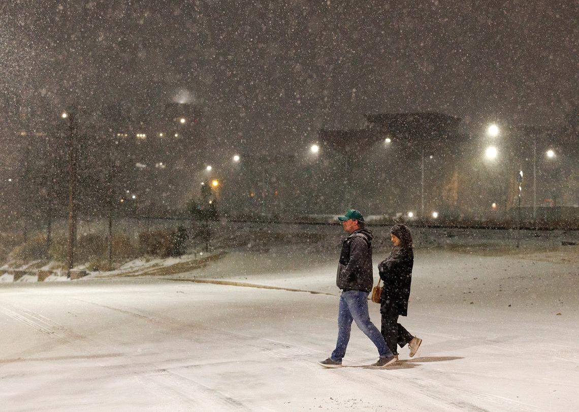 Pedestrians cross Pettigrew Street as snow falls in downtown Durham, N.C. on Tuesday, Jan. 21, 2025.
