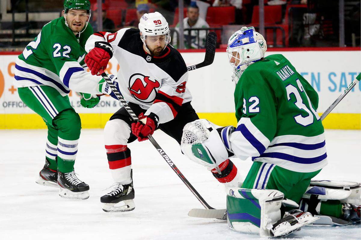 New Jersey Devils’ Tomas Tatar (90) drives the puck past Carolina Hurricanes’ Brett Pesce (22) to shoot at goaltender Antti Raanta (32) during the first period of an NHL hockey game in Raleigh, N.C., Saturday, Jan. 29, 2022. (AP Photo/Karl B DeBlaker)