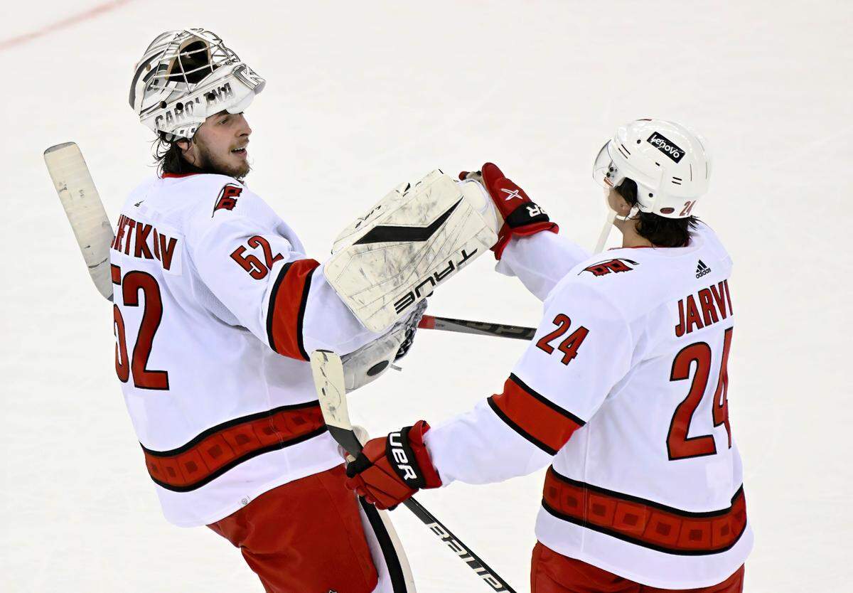 Carolina Hurricanes goaltender Pyotr Kochetkov (52) celebrates with center Seth Jarvis (24) after Jarvis scored the winning goal during the overtime period of an NHL hockey game to defeat the New Jersey Devils 3-2 Saturday, April 23, 2022, in Newark, N.J. (AP Photo/Bill Kostroun)