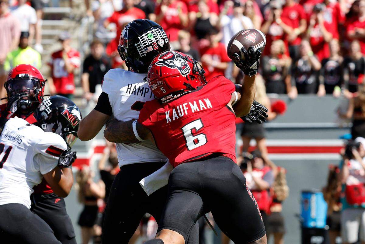 N.C. State’s DK Kaufman (5) knocks the ball from Northern Illinois quarterback Ethan Hampton (2) during the first half of N.C. State’s game against Northern Illinois at Carter-Finley Stadium in Raleigh, N.C., Saturday, Sept. 28, 2024. Kaufman would scoop up the loose ball and score.