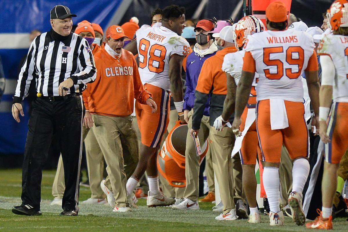 Clemson Tigers head coach Dabo Swinney, left, reacts after receiving a gatorade bath in the closing moments of the ACC Championship game to the amusement of an official. Clemson defeated Notre Dame 34-10 to win the championship at Bank of America Stadium in Charlotte, NC on Saturday, December 19, 2020.  